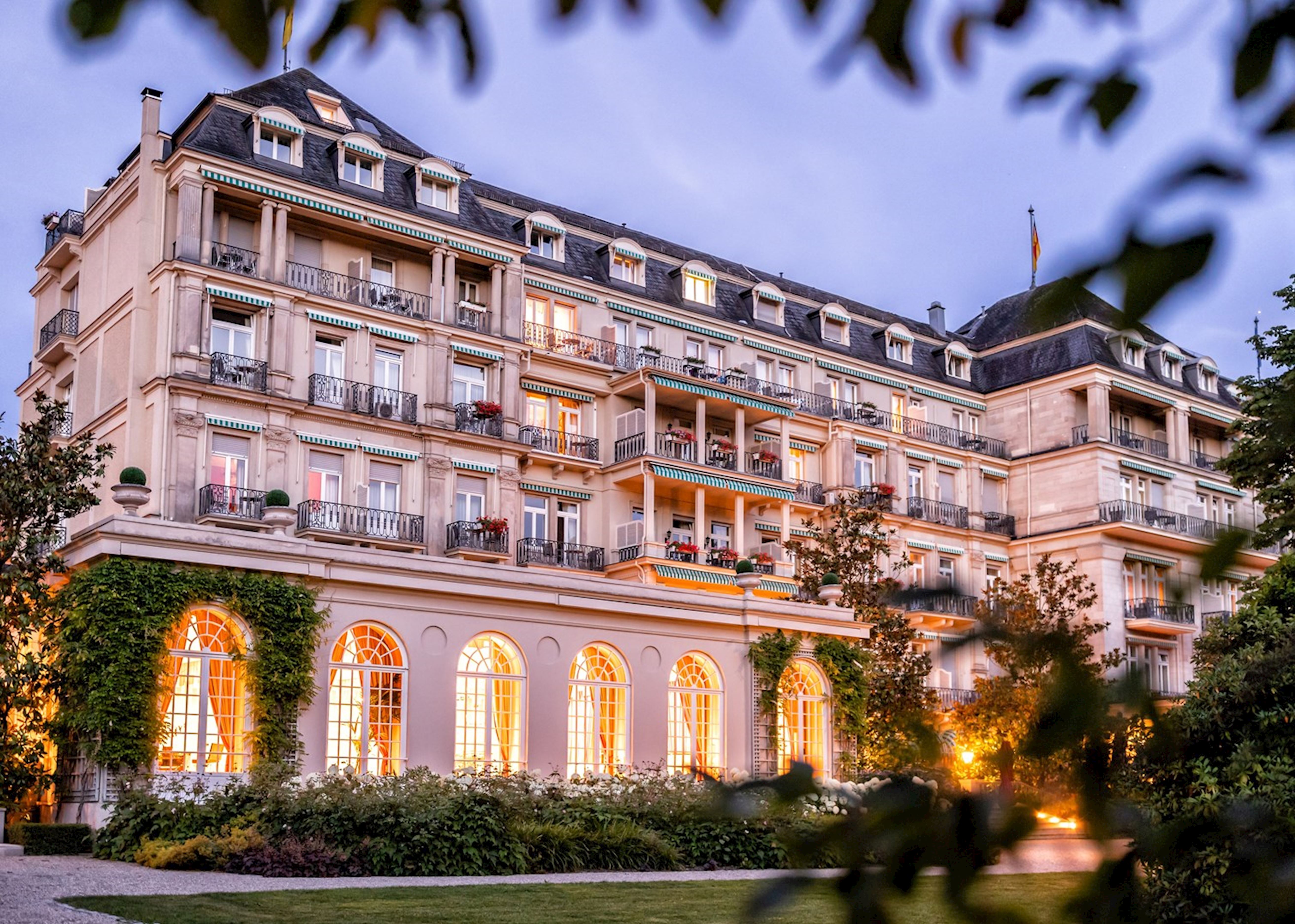 Exterior of a grand, luxurious hotel in Baden-Baden surrounded by parkland